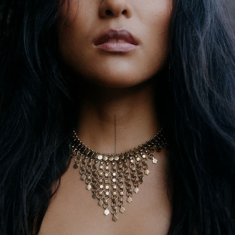 Handcrafted brass statement choker necklace with cascading ring fringe and mixed geometric charm drops, worn close to the throat.