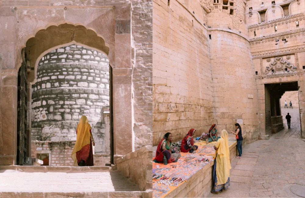 Scène de rue indienne avec des femmes en saris colorés discutant, et une femme en sari rose tenant la main d’un jeune garçon dans une cour ensoleillée. - NOIR KĀLA