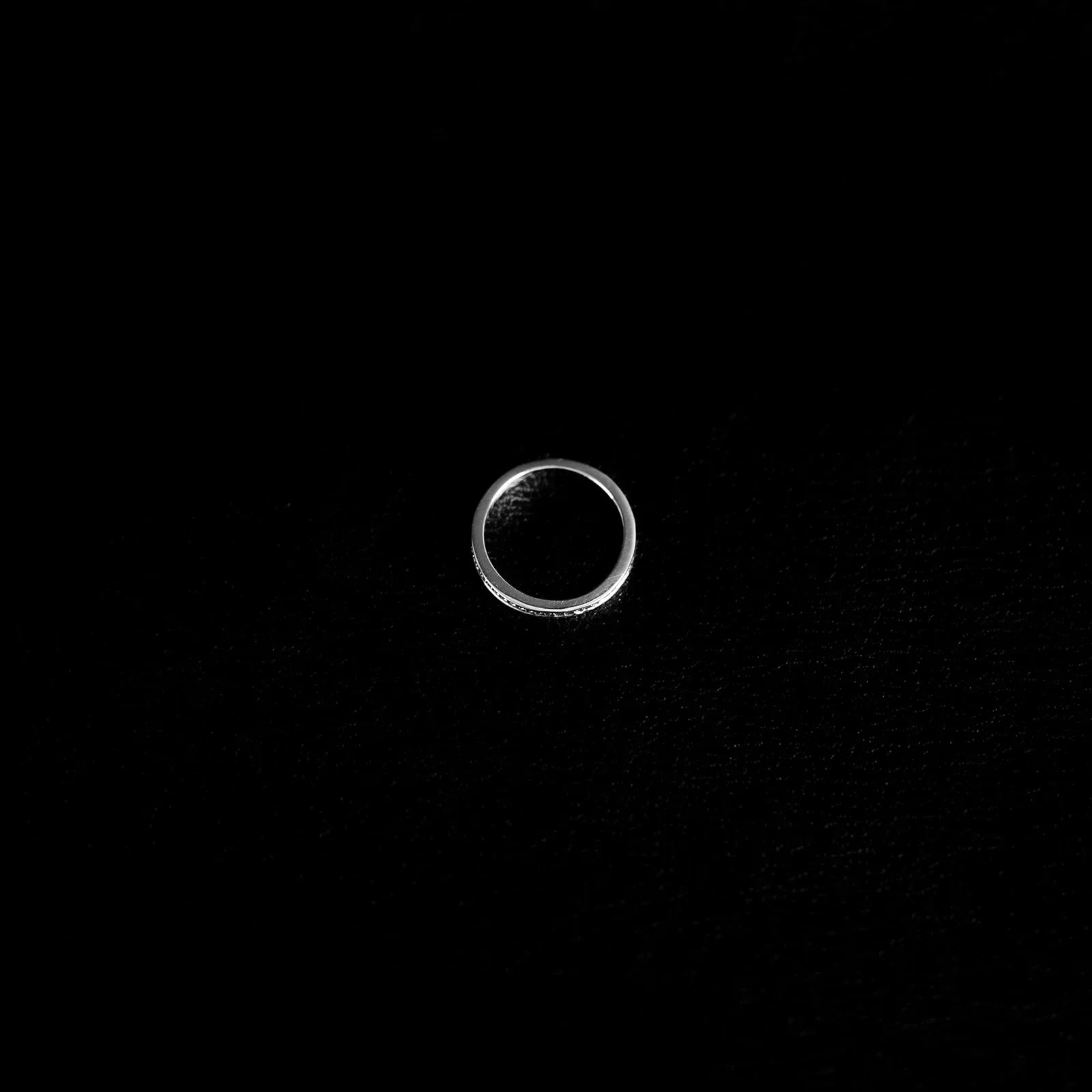 Slender textured 925 sterling silver band ring on a finger, with fine faceted detailing and polished finish.