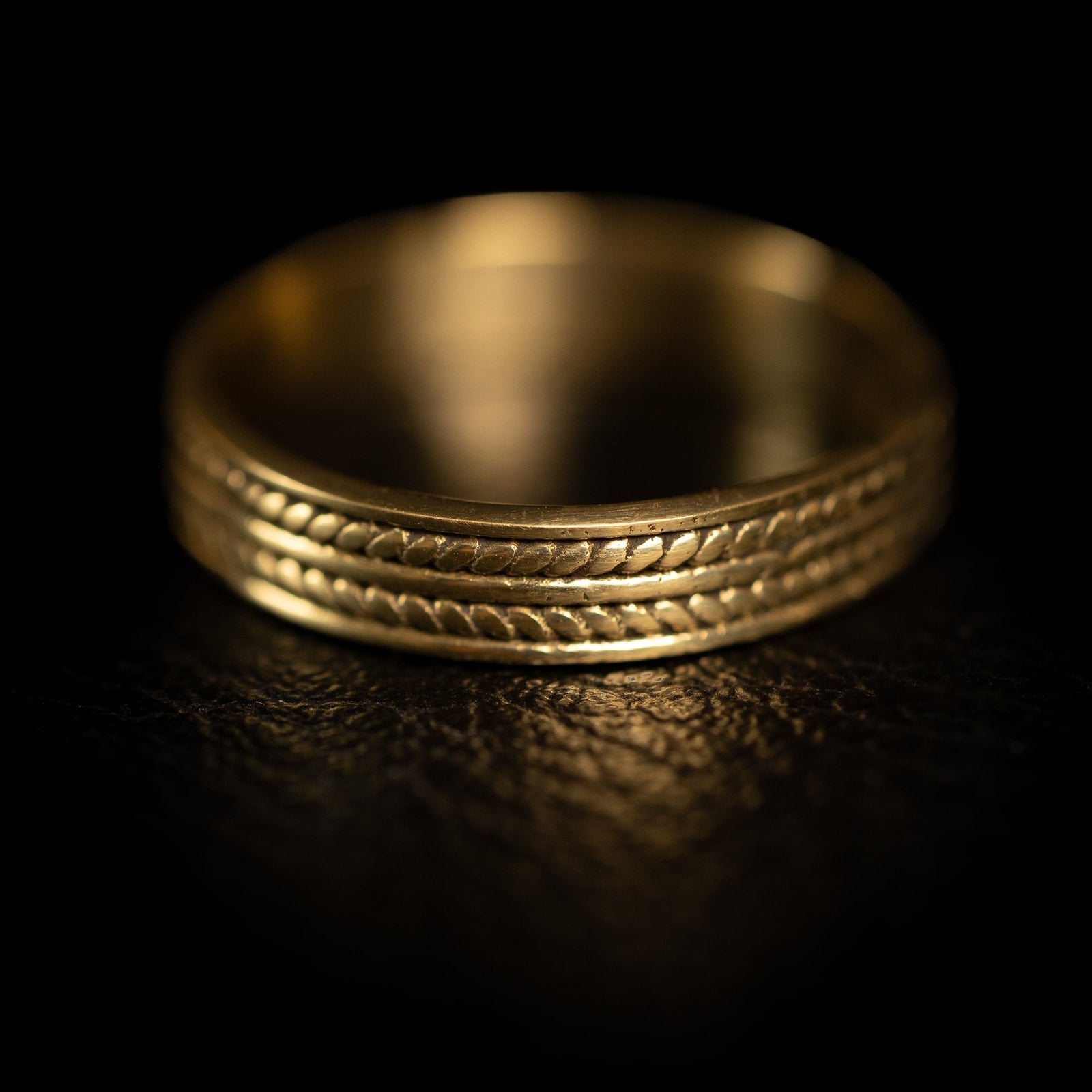 Wide band ring in 22K gold plated finish with a twisted rope pattern carved along both edges.