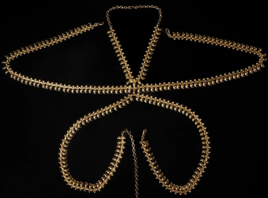 A woman wearing brass hoop earrings layered with necklaces illustrates the weight and warmth that make brass jewelry's benefits hard to replicate.